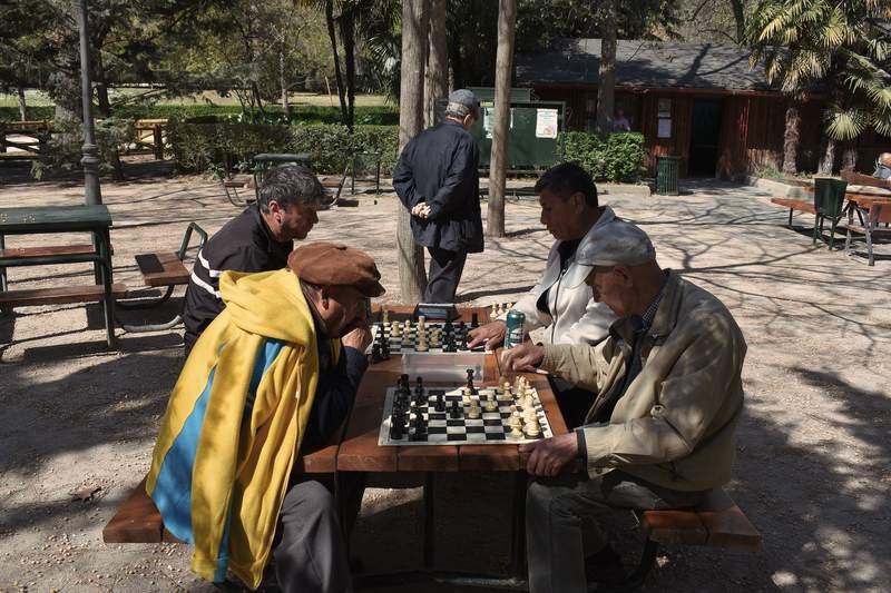 Hommes âgés concentrés sur une partie d'échecs en plein air, sur une table d'un parc ensoleillé de Madrid