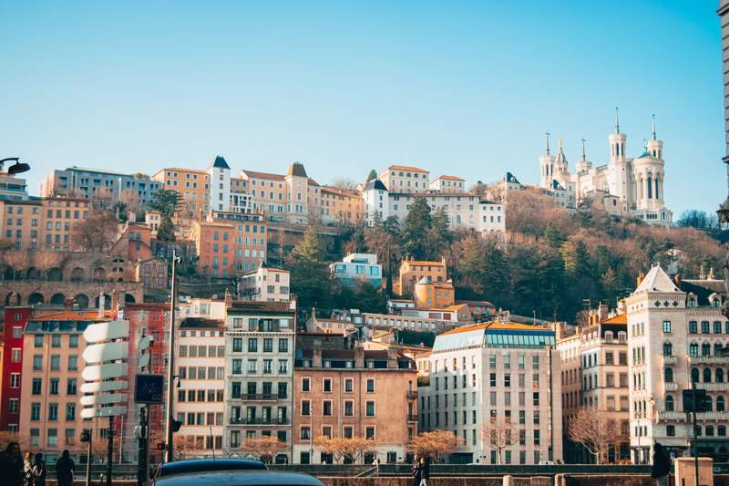 Vue de Lyon : façades colorées au bord de la Saône et colline de Fourvière couronnée de sa basilique.