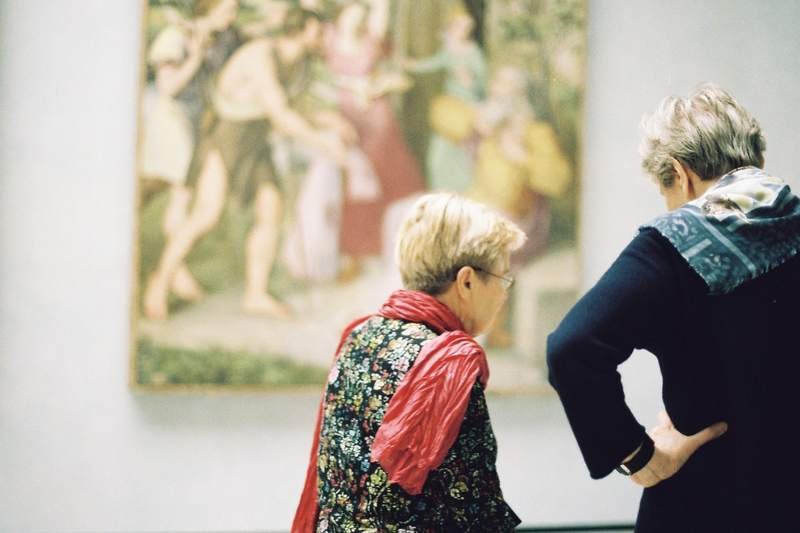 Deux femmes âgées observant ensemble un tableau accroché au mur d'une salle de musée des beaux-arts